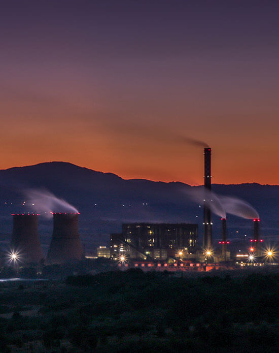 Foto de uma industria de energia, com montanhas e por do sol atrás